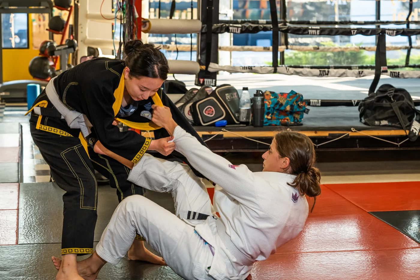 Two Brazilian Jiu-Jitsu practitioners grappling on the mats.