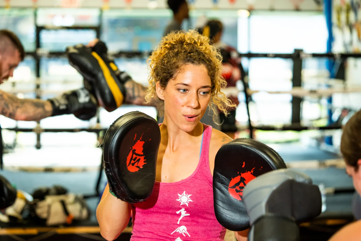 Cara Denney holding focus mitts while coaching in the ring at CJ Martial Arts.